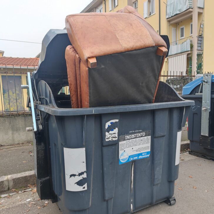 Un divano infilato in un cassonetto di corso Romita: ad Alessandria l’ennesimo episodio di degrado